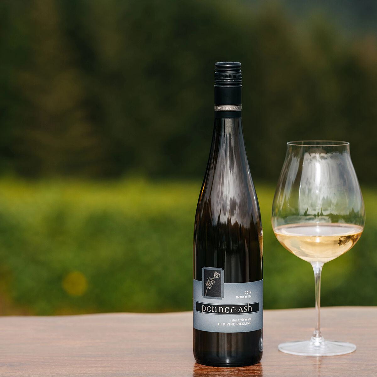 A wine bottle of Penner-Ash Riesling next to a wine glass full.